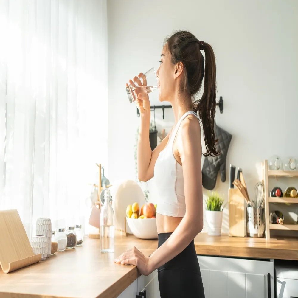 Fit woman drinking hydrogen water in modern kitchen